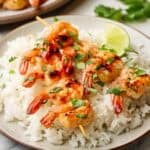 shrimp skewers served over a bed of rice on a plate