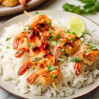 shrimp skewers served over a bed of rice on a plate