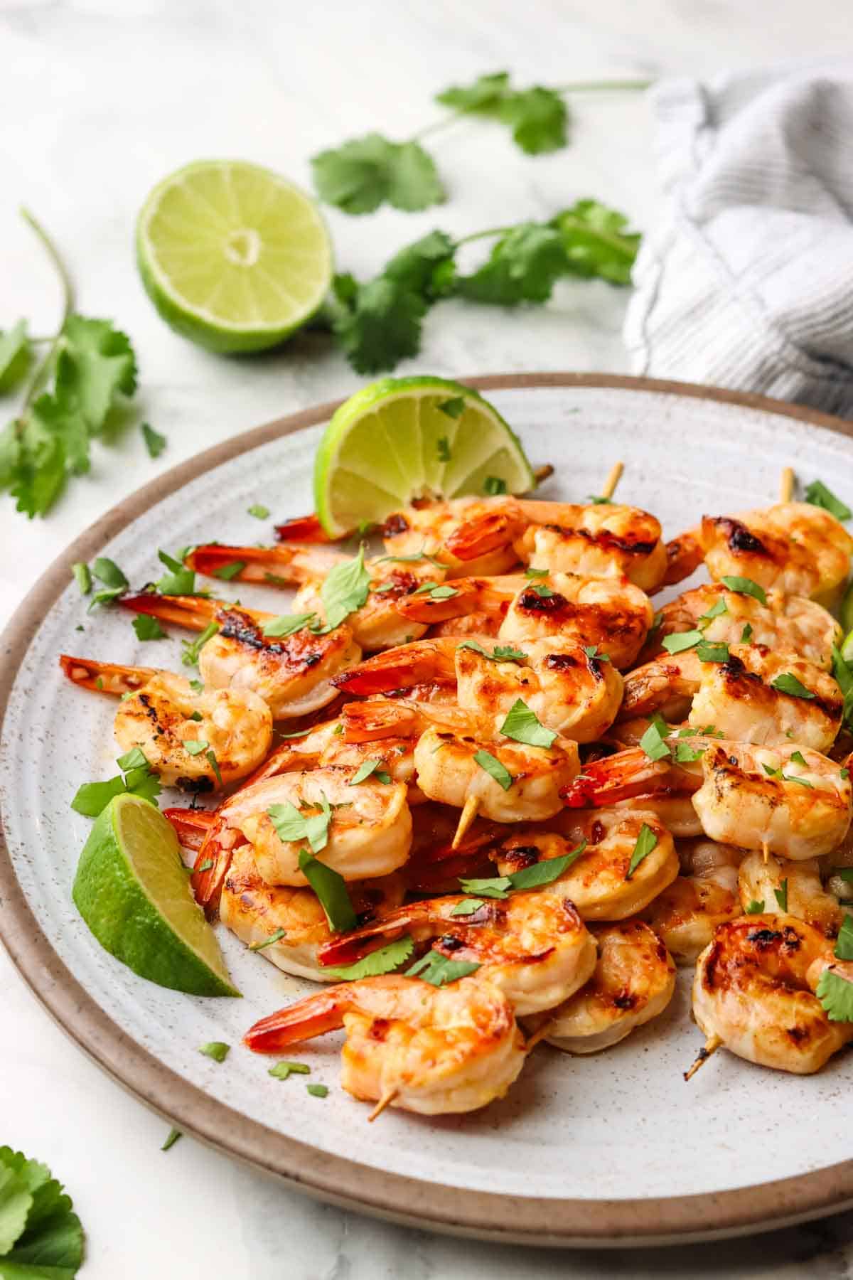 a plate with chili lime shrimp skewers served with a wedge of lime.