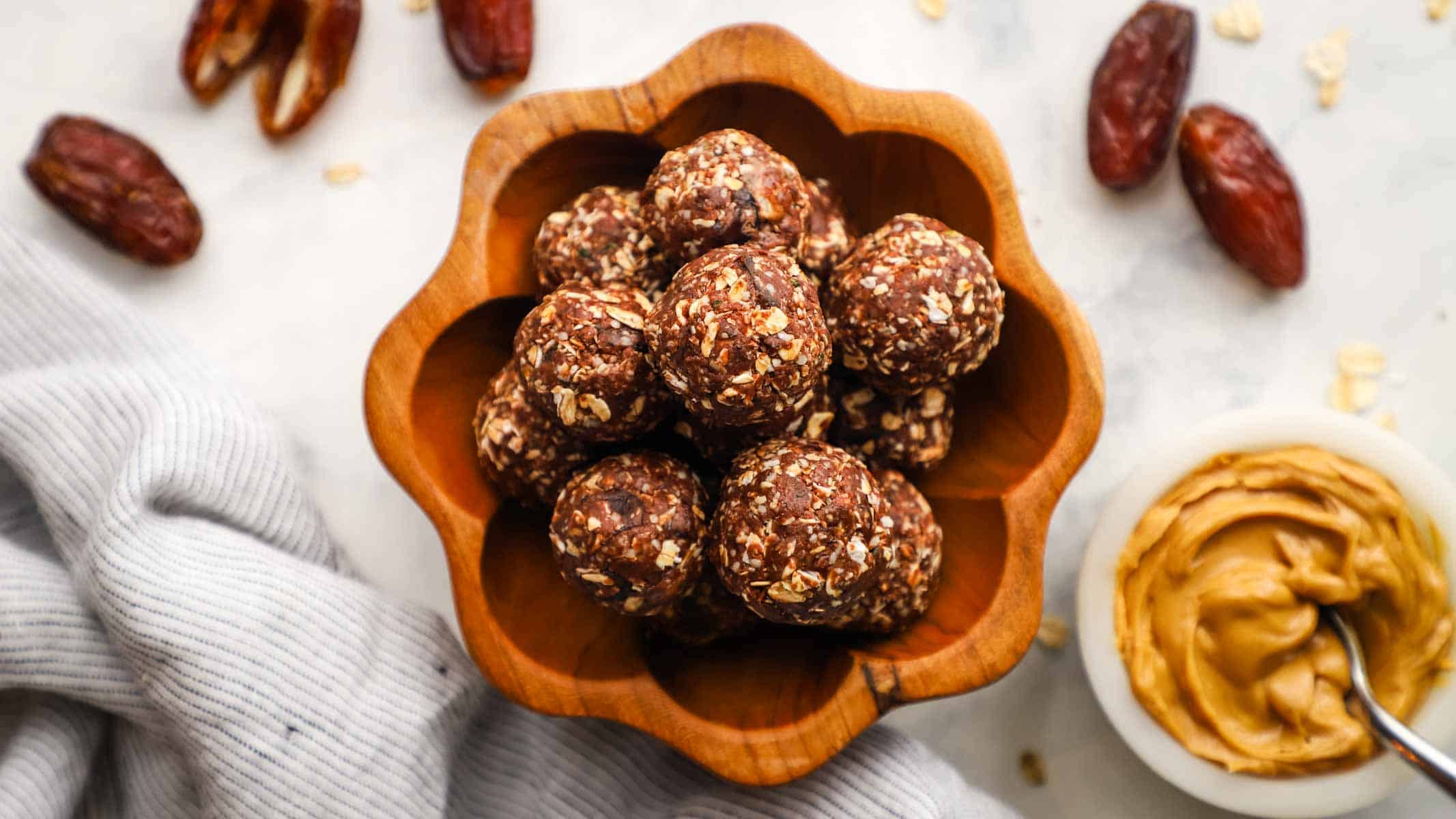 A top-down view of chocolate peanut butter protein balls stacked in a wooden bowl.