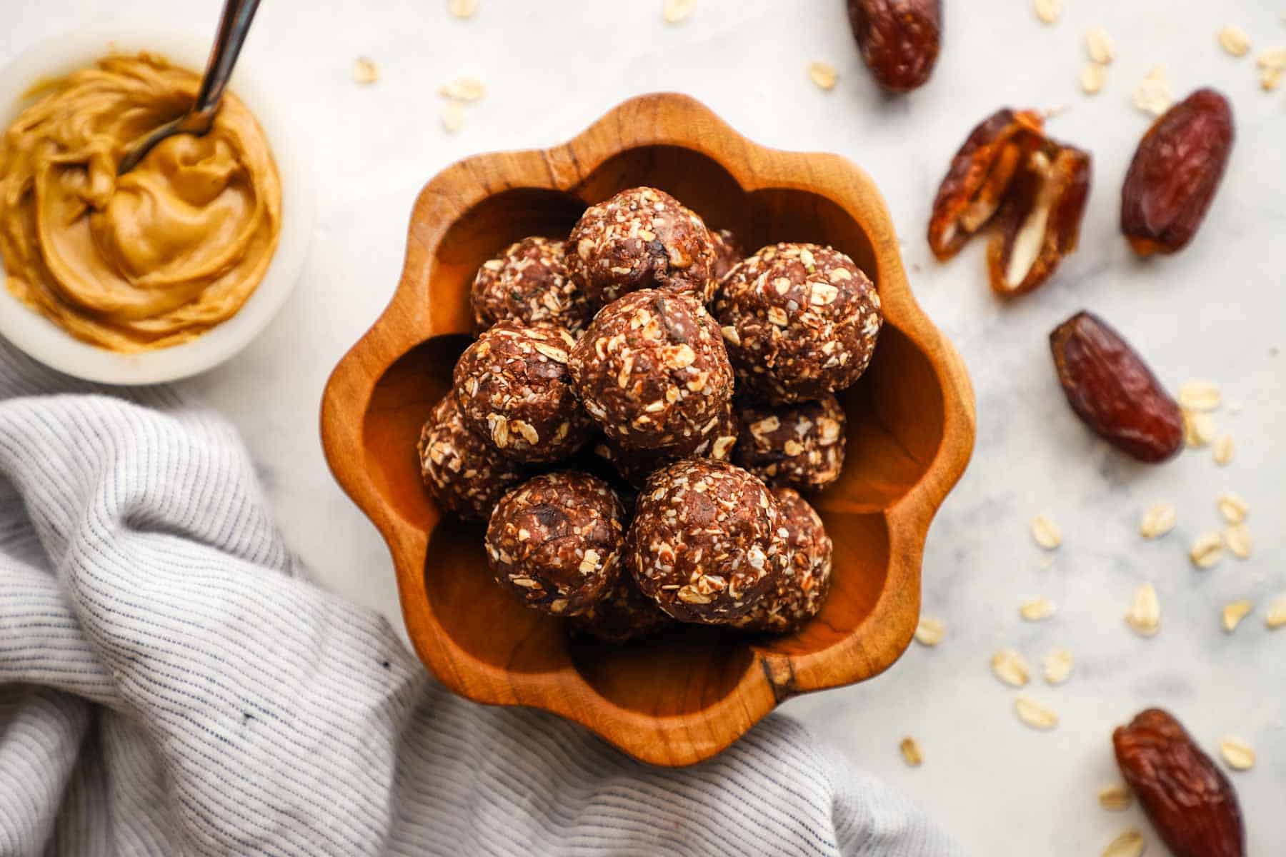 A top-down view of chocolate peanut butter protein balls stacked in a wooden bowl.