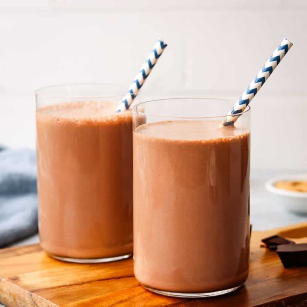 Two peanut butter chocolate smoothies with straws.