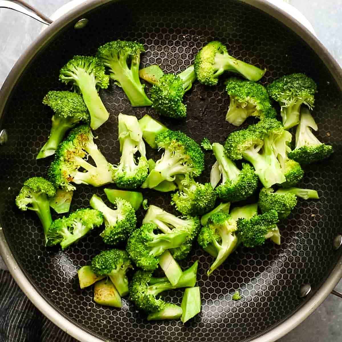 Top-down view of broccoli now in the skillet once the park has been removed and being sautéed in a light amount of oil. 