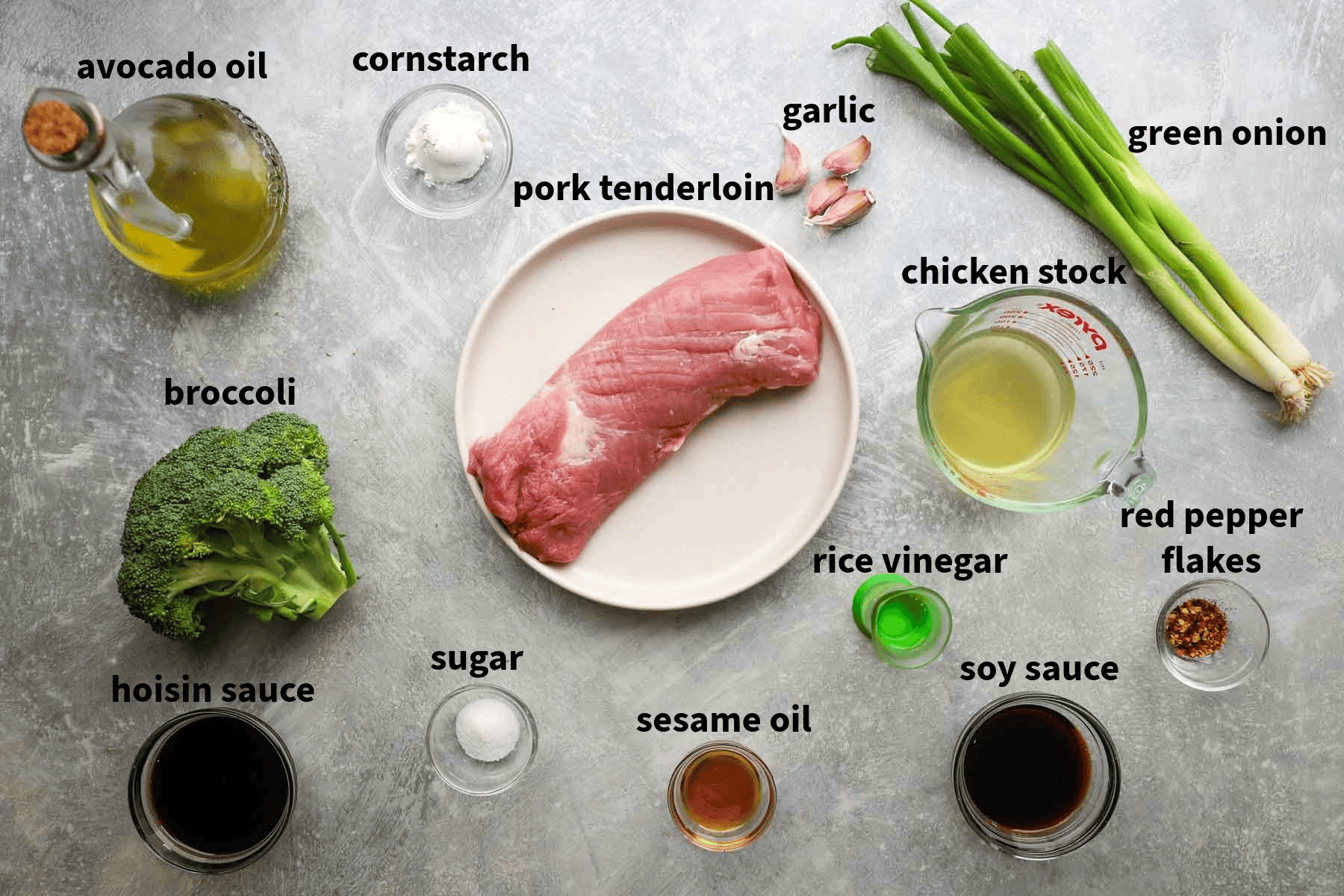 Top-down view of stir fry ingredients that include pork tenderloin, garlic, rice vinegar, sesame seed oil, broccoli, and more to be used for Pork and Broccoli stir fry. 