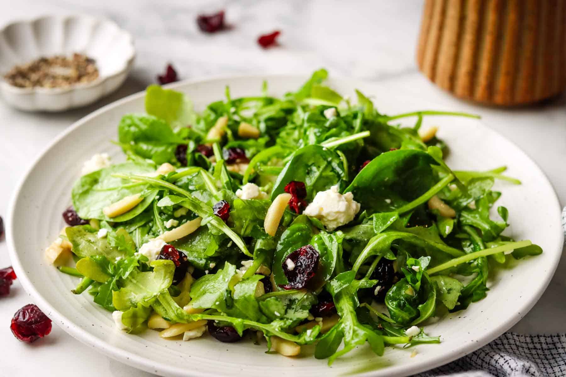 Fresh spinach arugula salad with dried cranberries, almonds, and crumbled feta cheese.