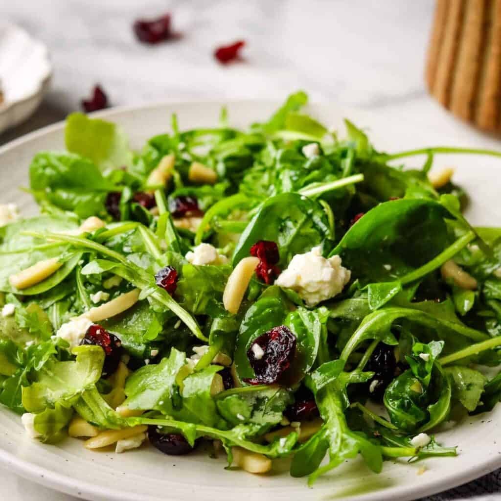 Fresh spinach arugula salad with dried cranberries, almonds, and crumbled feta cheese.