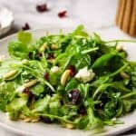 Fresh spinach arugula salad with dried cranberries, almonds, and crumbled feta cheese.