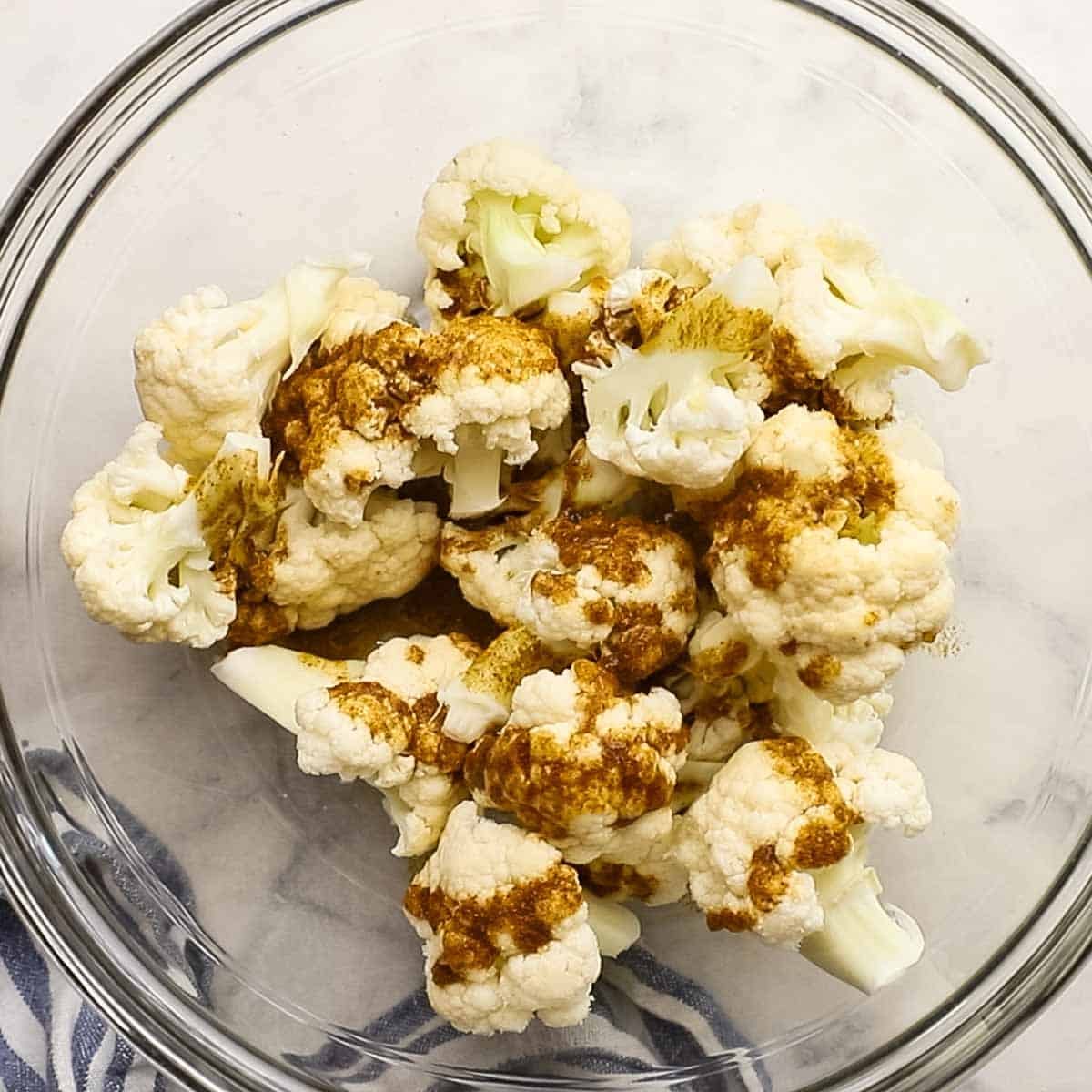 cauliflower florets tossed in a spice mixture in a small bowl