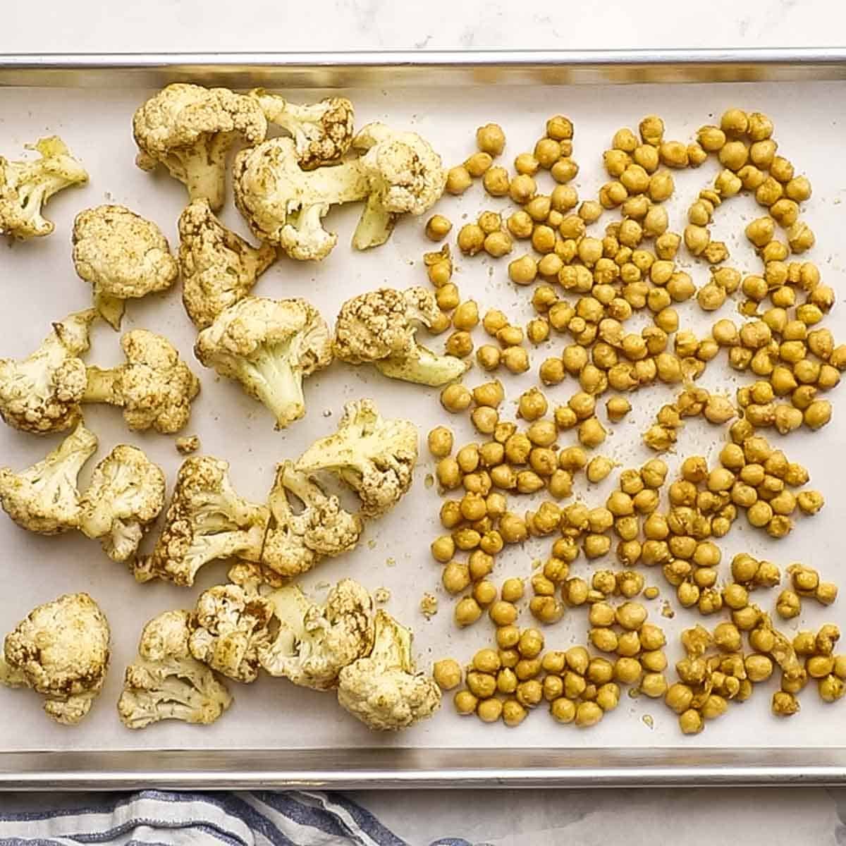 cauliflower and chickpeas spread in a single layer on a baking sheet