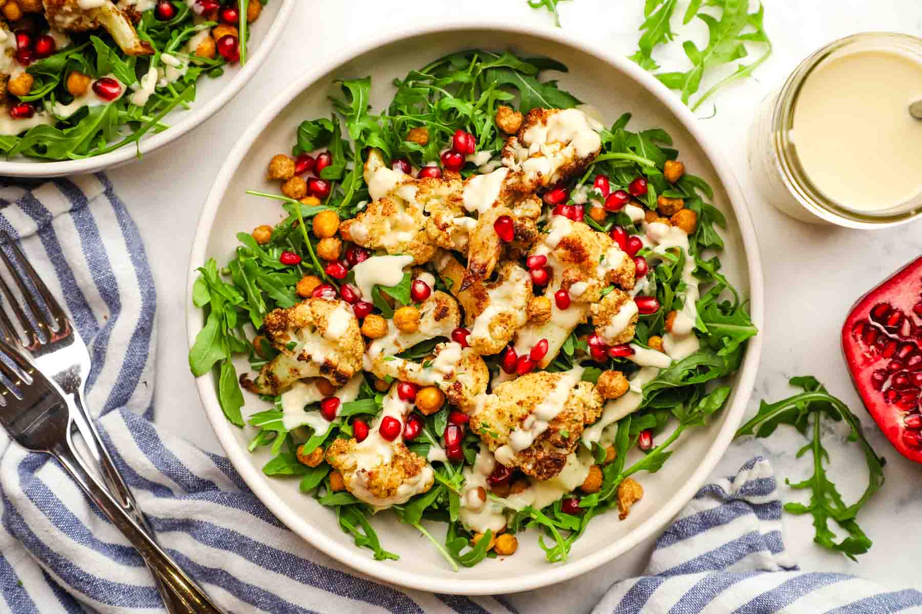 roasted cauliflower salad with arugula, pomegranate seeds, and creamy dressing.
