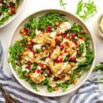 roasted cauliflower salad with arugula, pomegranate seeds, and creamy dressing.