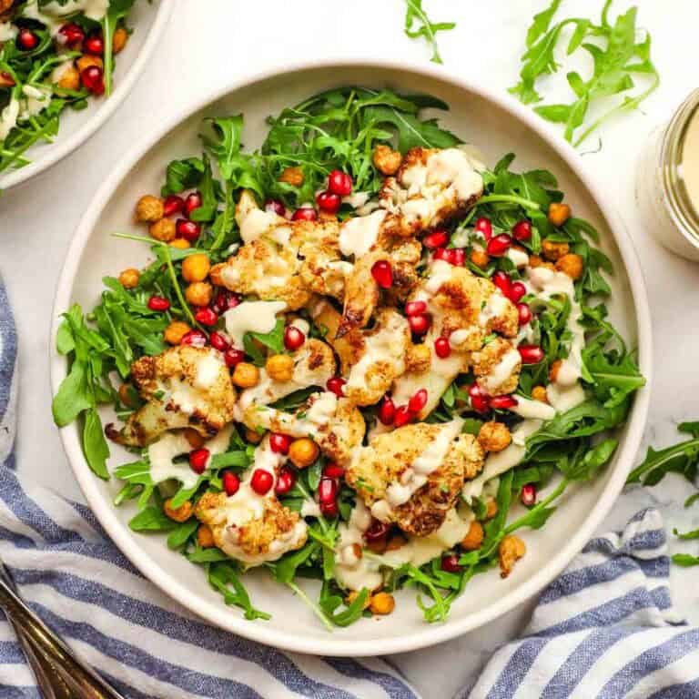 roasted cauliflower salad with arugula, pomegranate seeds, and creamy dressing.