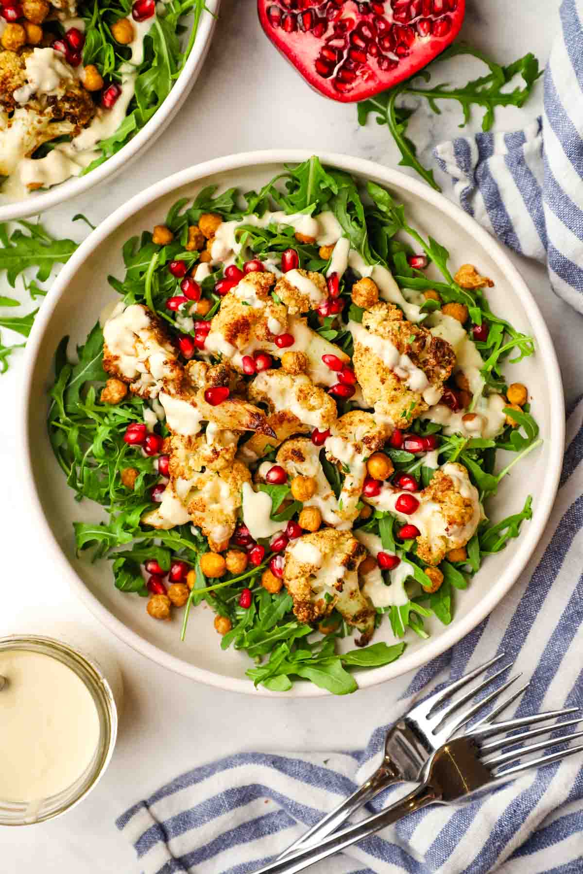 roasted cauliflower salad with arugula, pomegranate seeds, and creamy dressing.