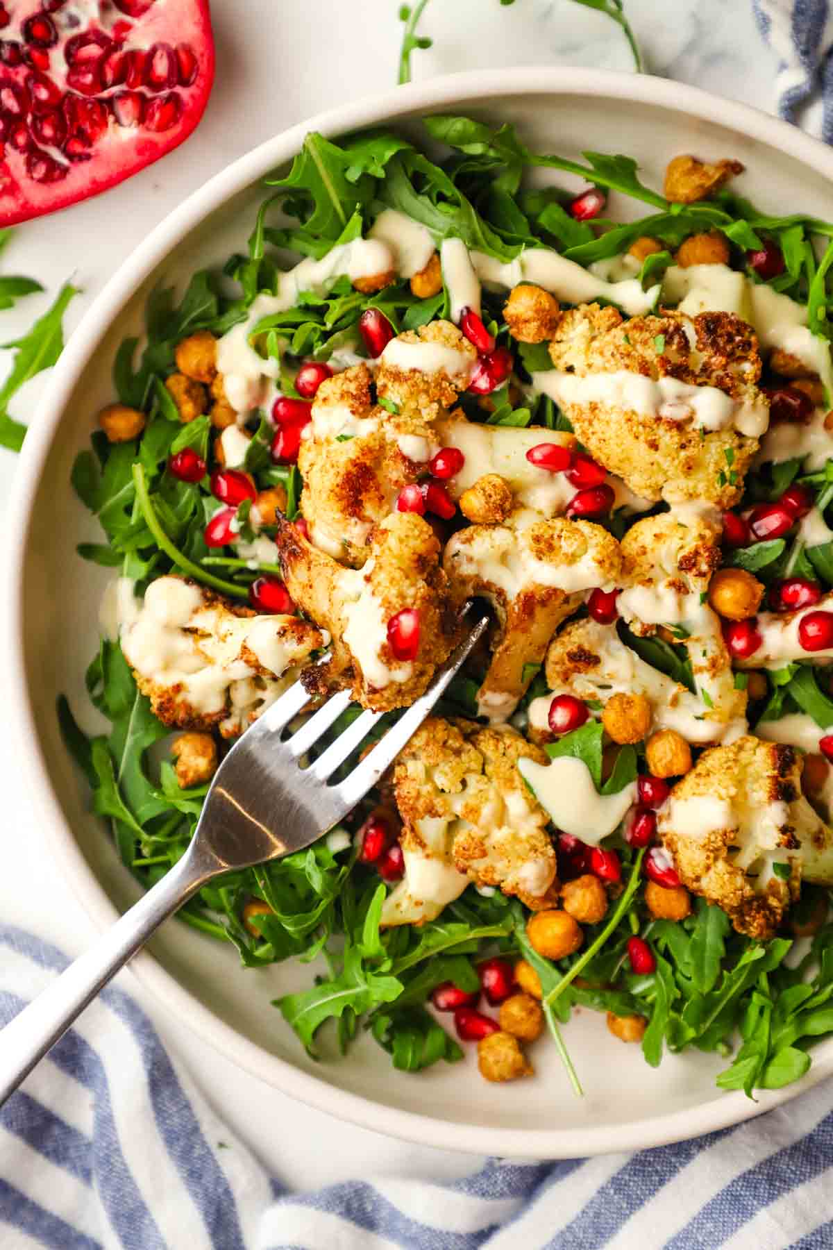 roasted cauliflower salad with arugula, pomegranate seeds, and creamy dressing.