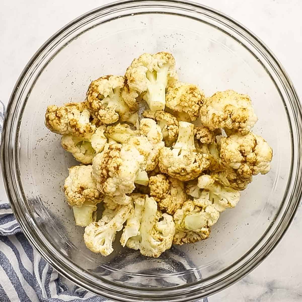 cauliflower florets tossed in a spice mixture in a small bowl