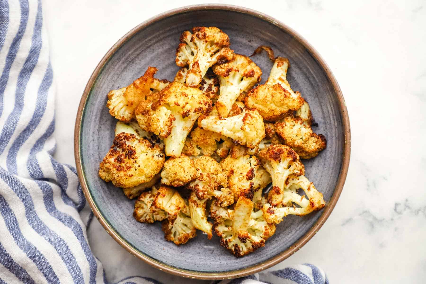 Baked cauliflower florets on a gray plate.