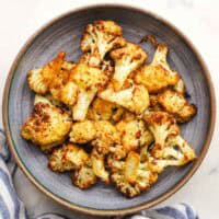 Crispy roasted cauliflower bites garnished with parsley in a bowl.