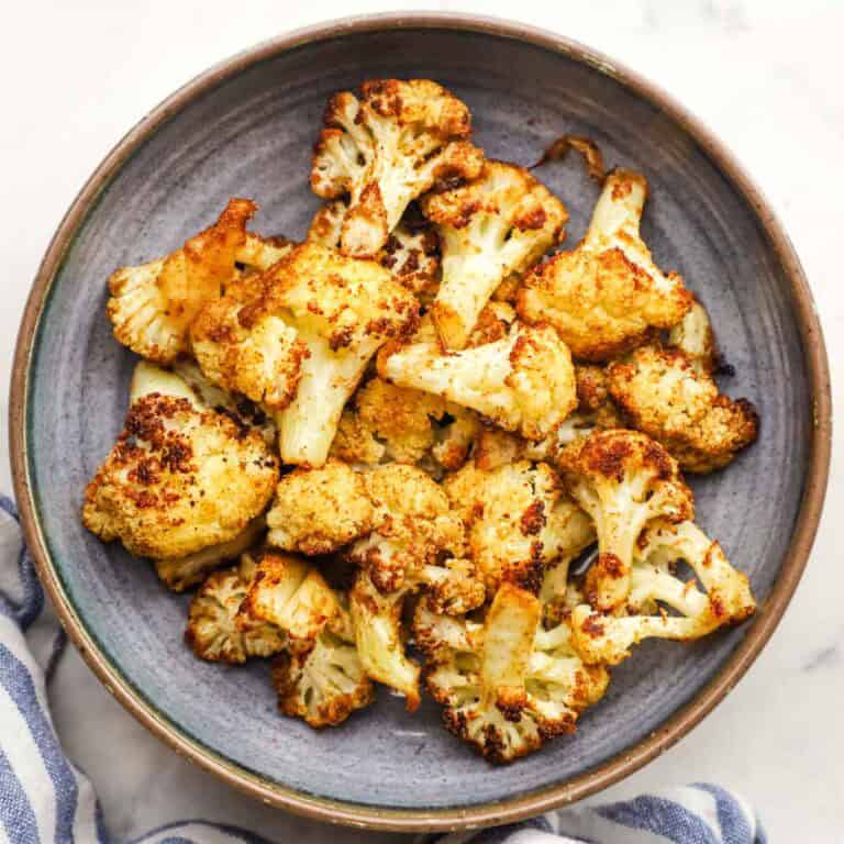 Crispy roasted cauliflower bites garnished with parsley in a bowl.