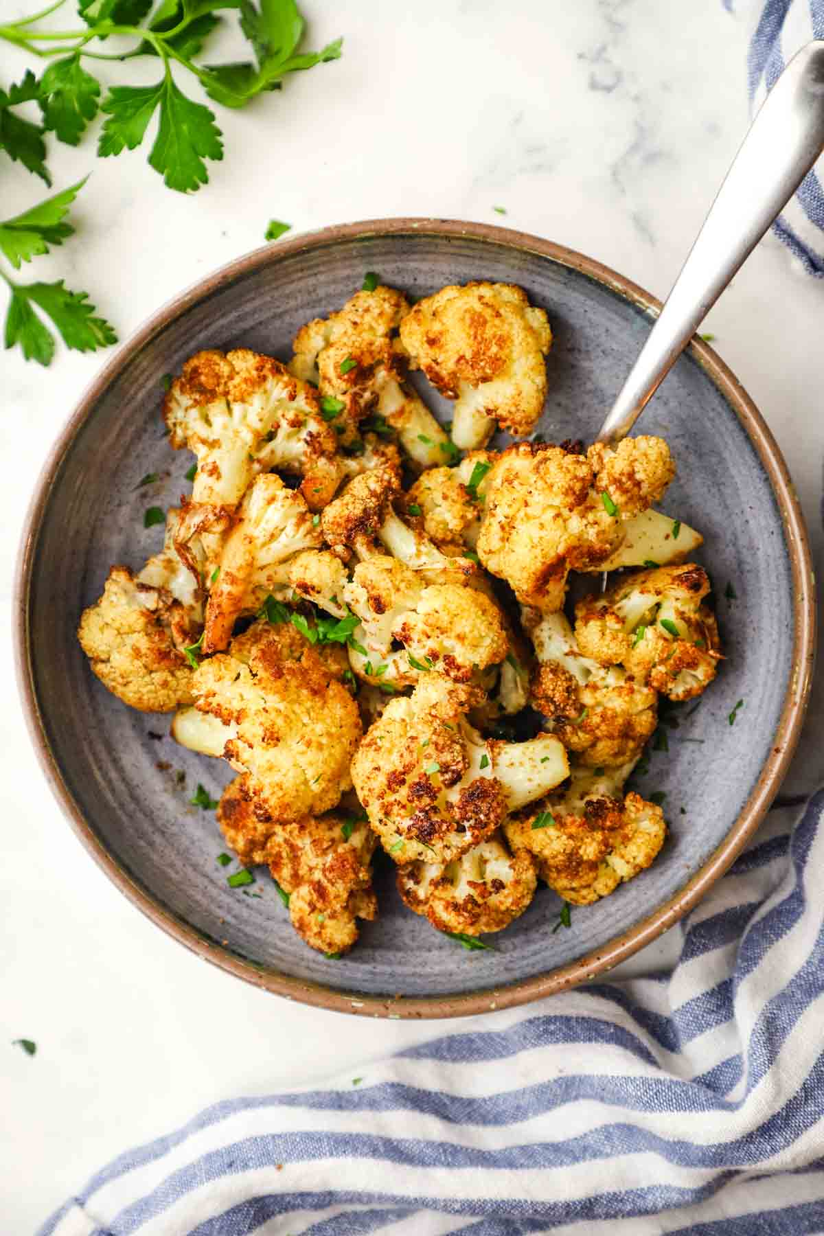 Crispy roasted cauliflower bites garnished with parsley in a bowl.