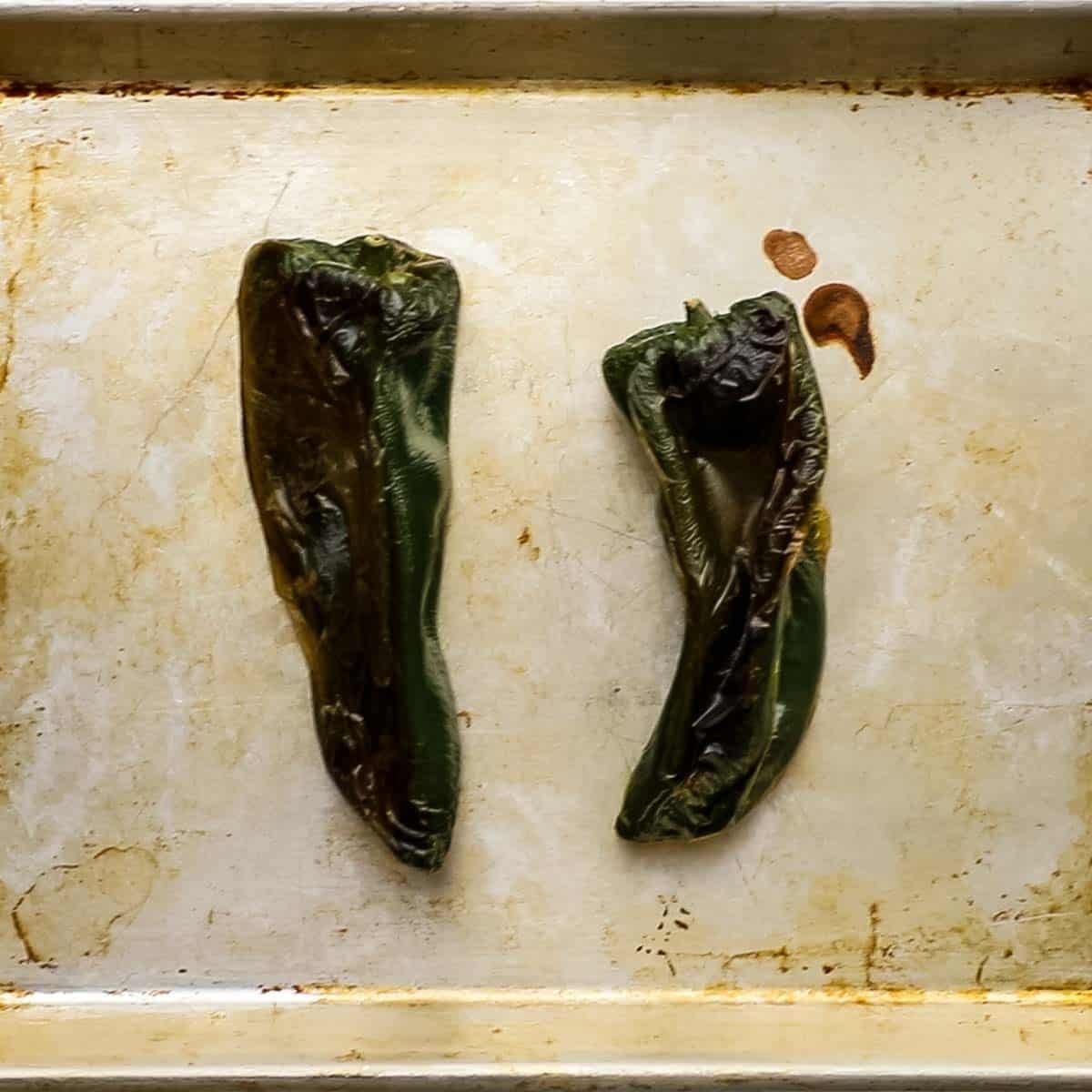 Top-down view of roasted poblano peppers on a sheet pan.