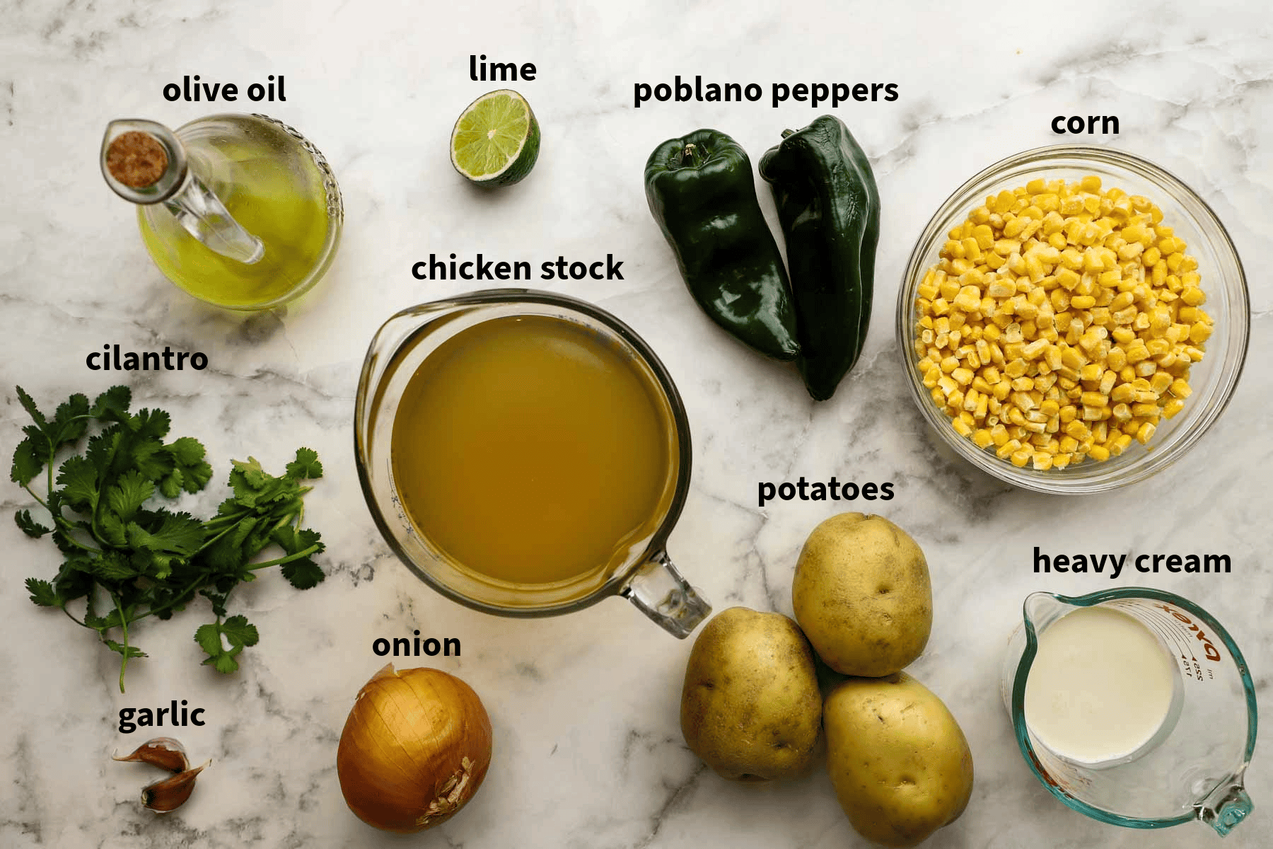 Top-down view of ingredients for roasted poblano soup which include poblano peppers, limes, potatoes, onion, corn olive oil and more. 
