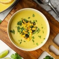 A bowl of roasted poblano corn and potato soup garnished with chopped corn, poblanos and cilantro.