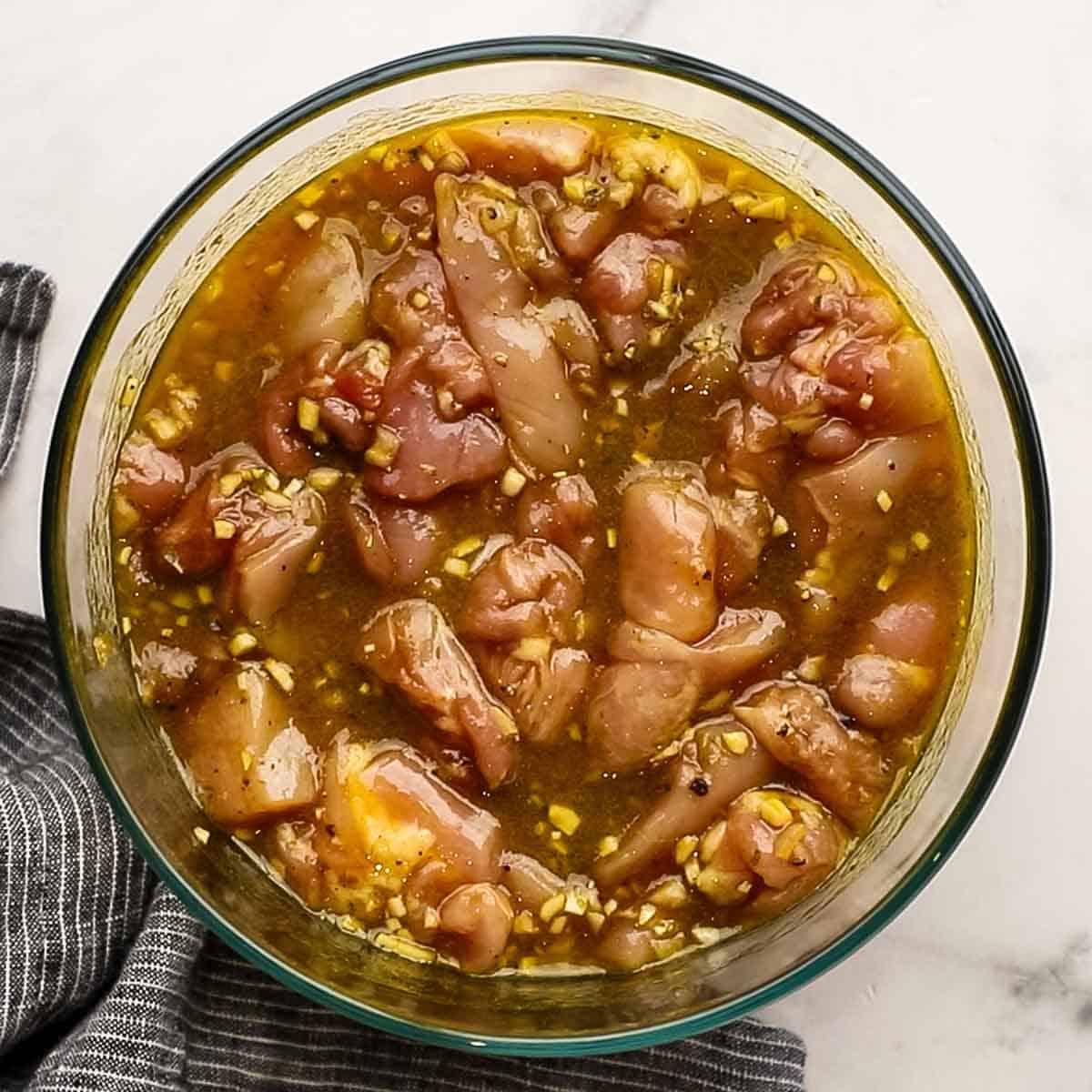 Chicken marinating in fish sauce, soy sauce, turmeric, shallot, mixture.