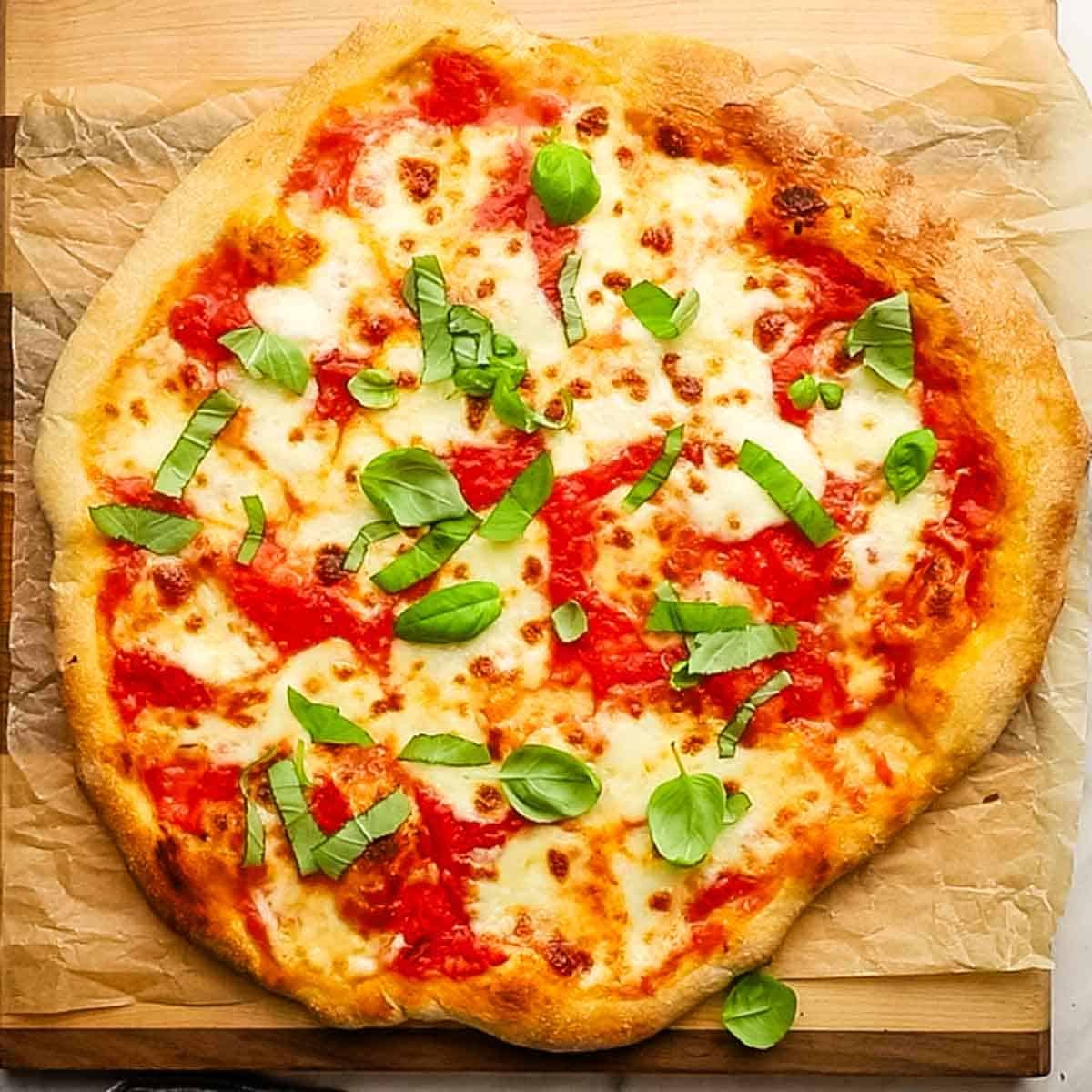 A whole margherita pizza on a wooden cutting board.