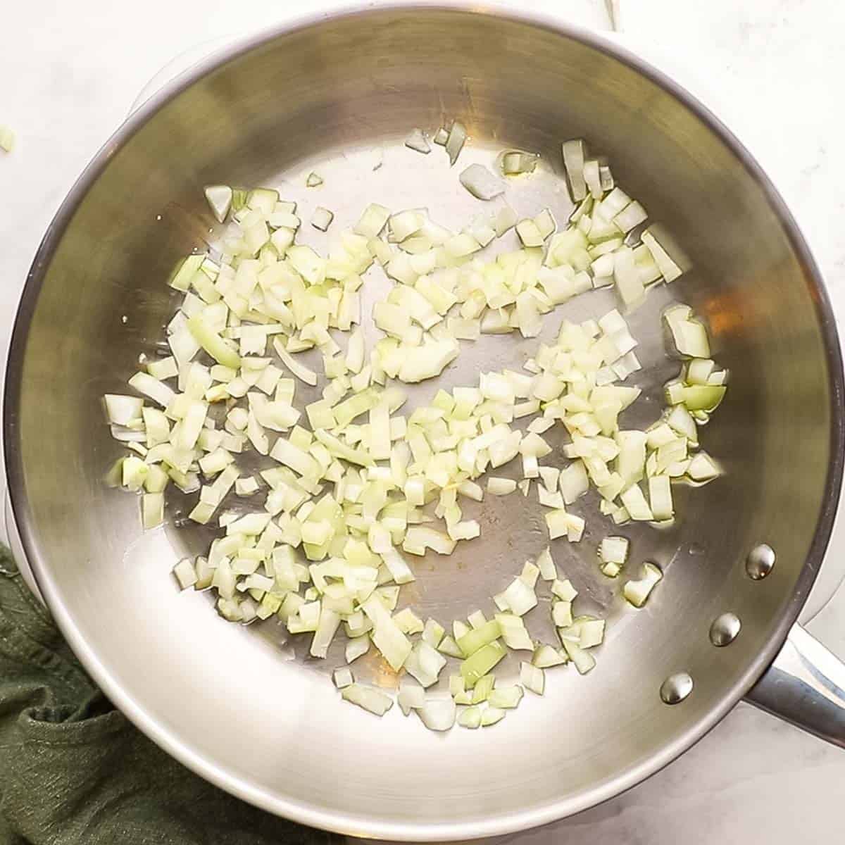 White onion and garlic being sauted for sauteed corn and zucchini. 