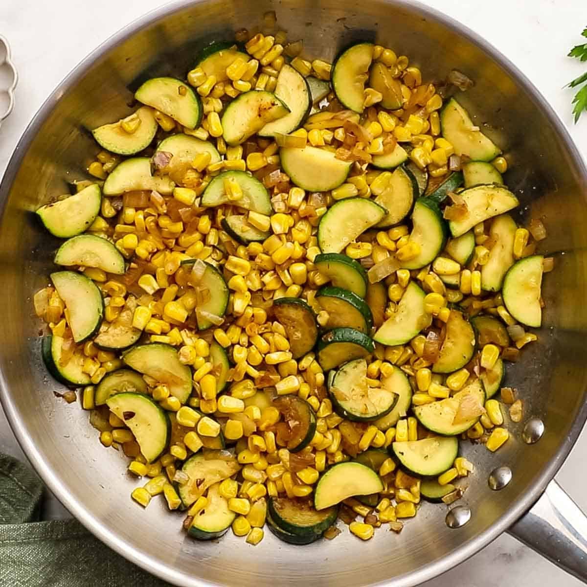 A pan of sauteed corn and zucchini that has been cooked in a skillet ready to be topped with garnishes.