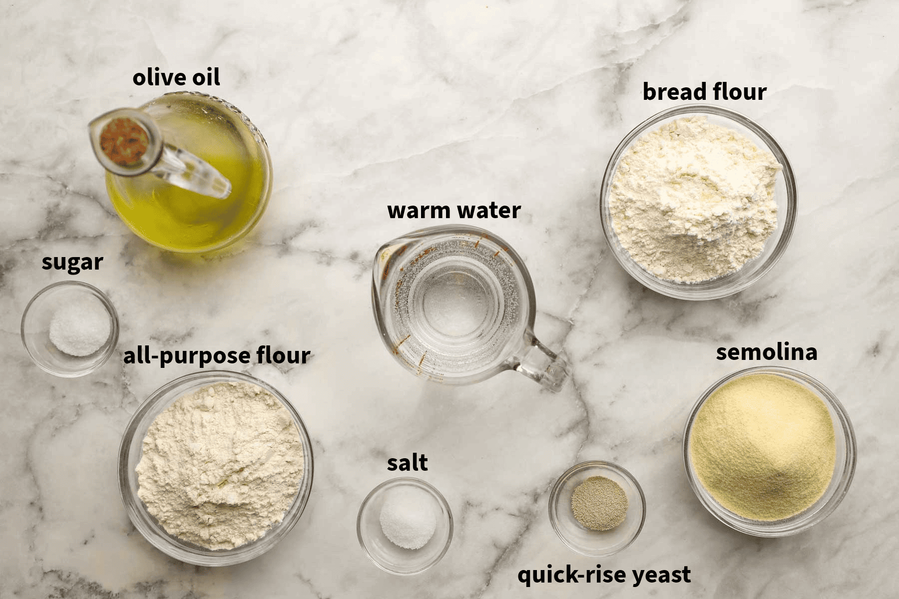 Top-down view of thin curst pizza dough ingredients that include olive oil, bread flour, all purpose flour, and semolina flour.
