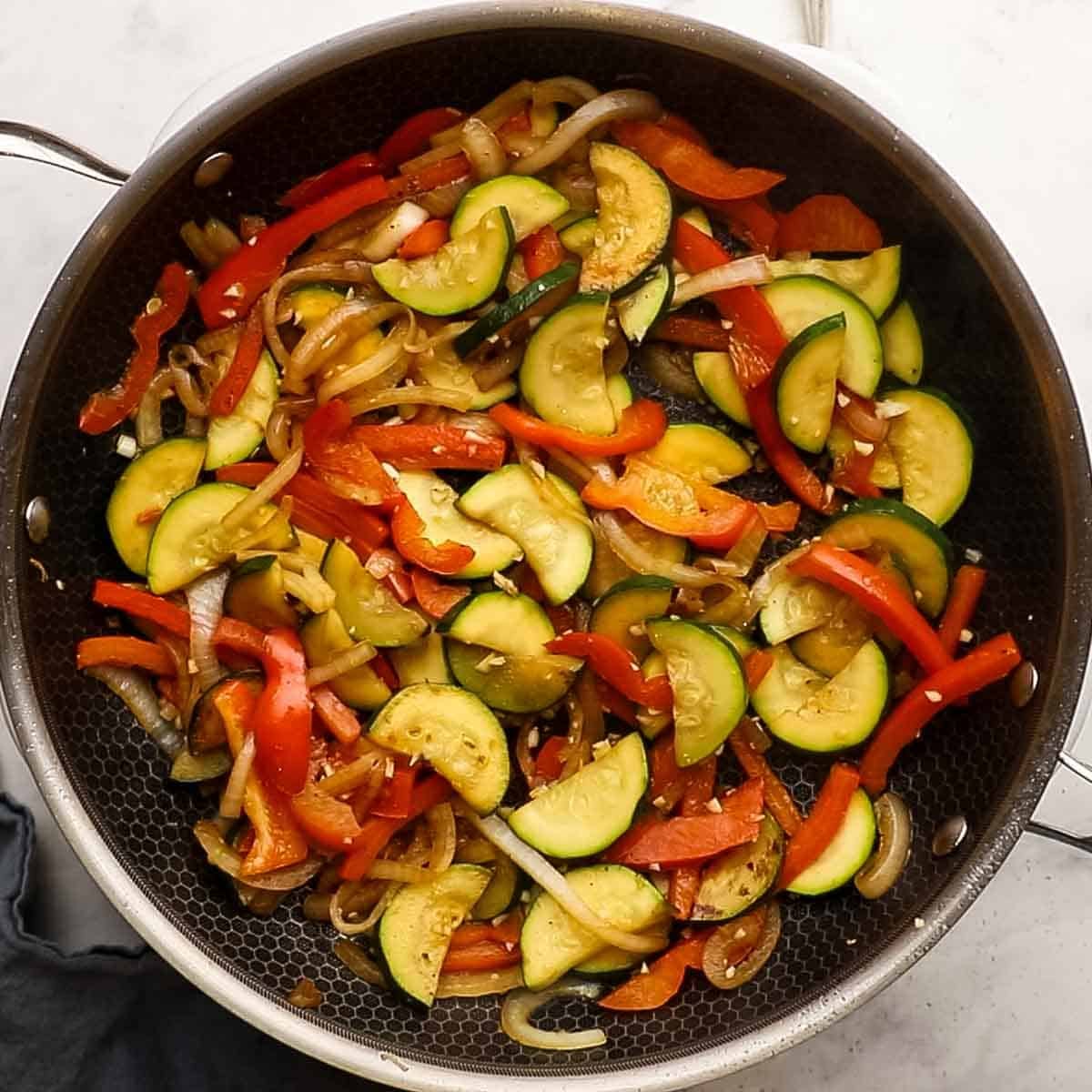 Onion, bell pepper, zucchini in added to the cooked chicken in the stir fry. 