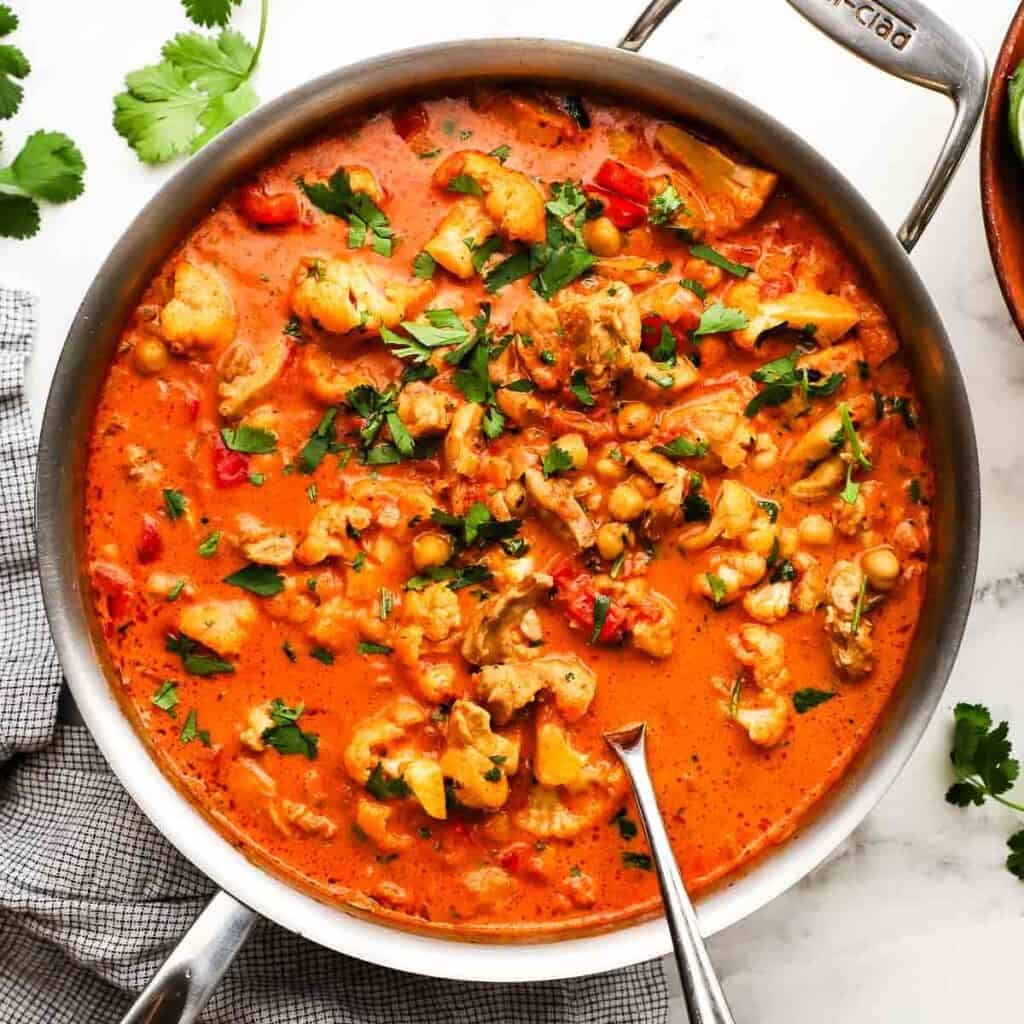 A pan of chicken and chickpea curry garnished with cilantro.