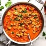 A pan of chicken and chickpea curry garnished with cilantro.