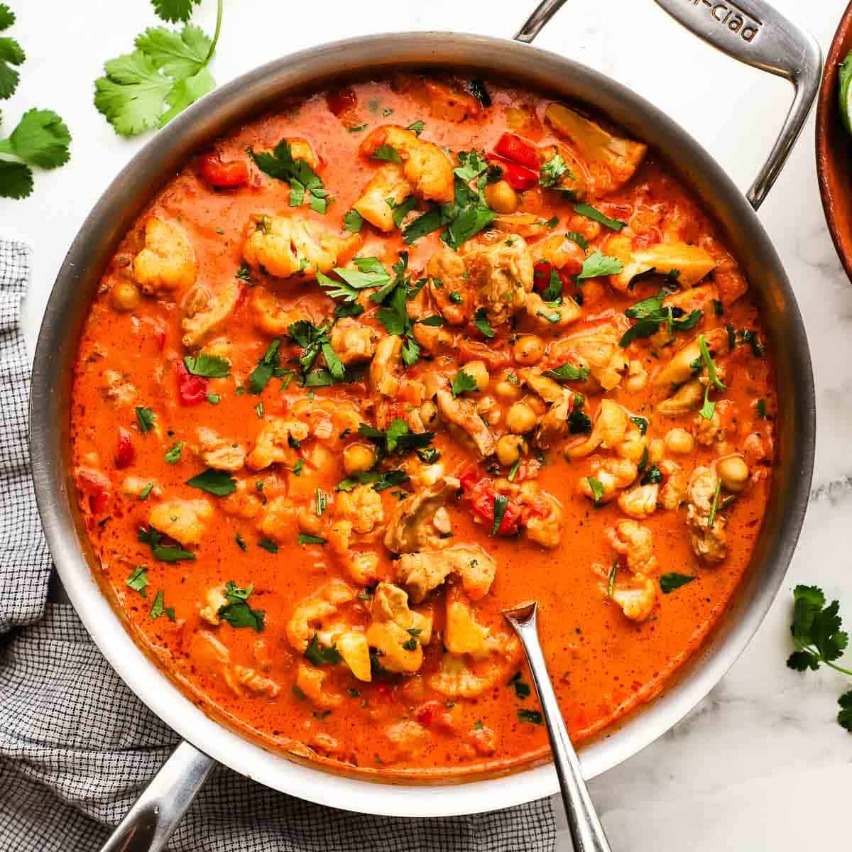 A pan of chicken and chickpea curry garnished with cilantro.