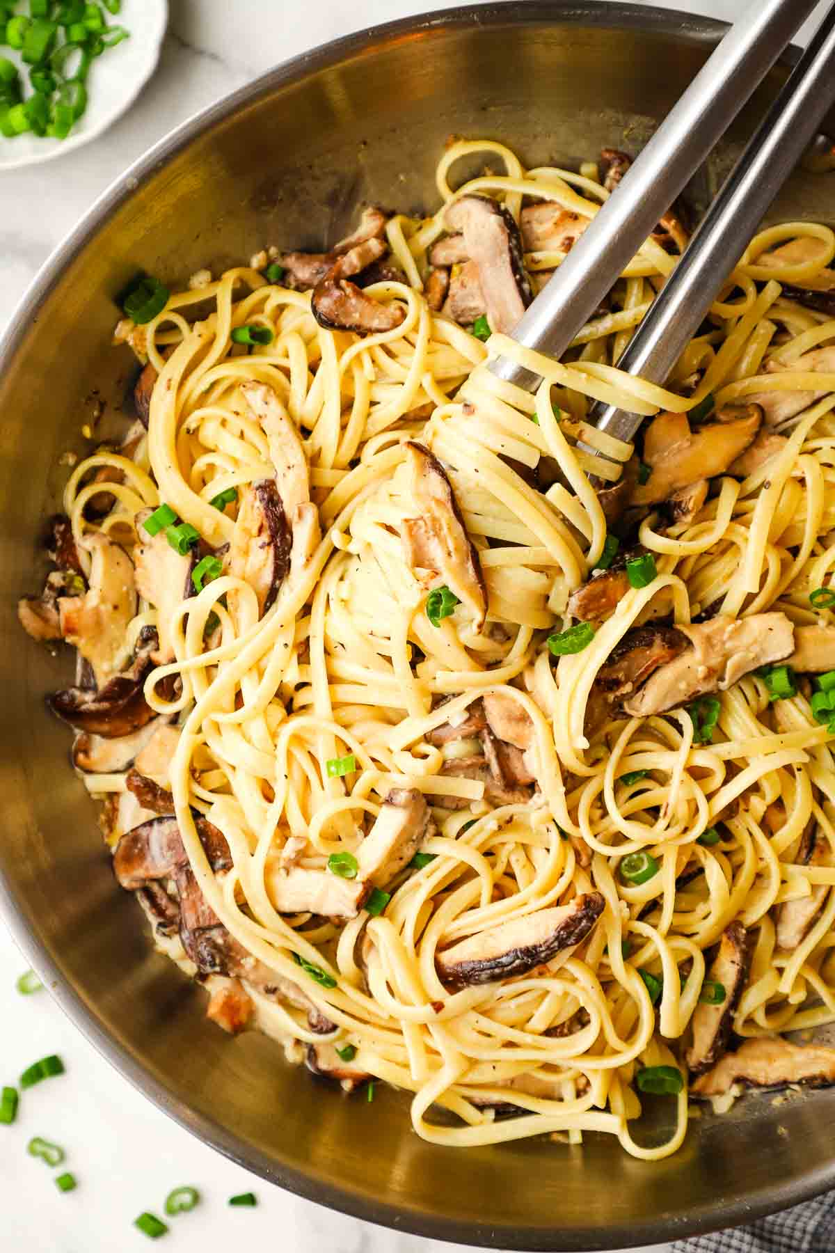 Miso Mushroom Pasta ready to be served with tongs, gently stirring and preparing to dollop on a plate.