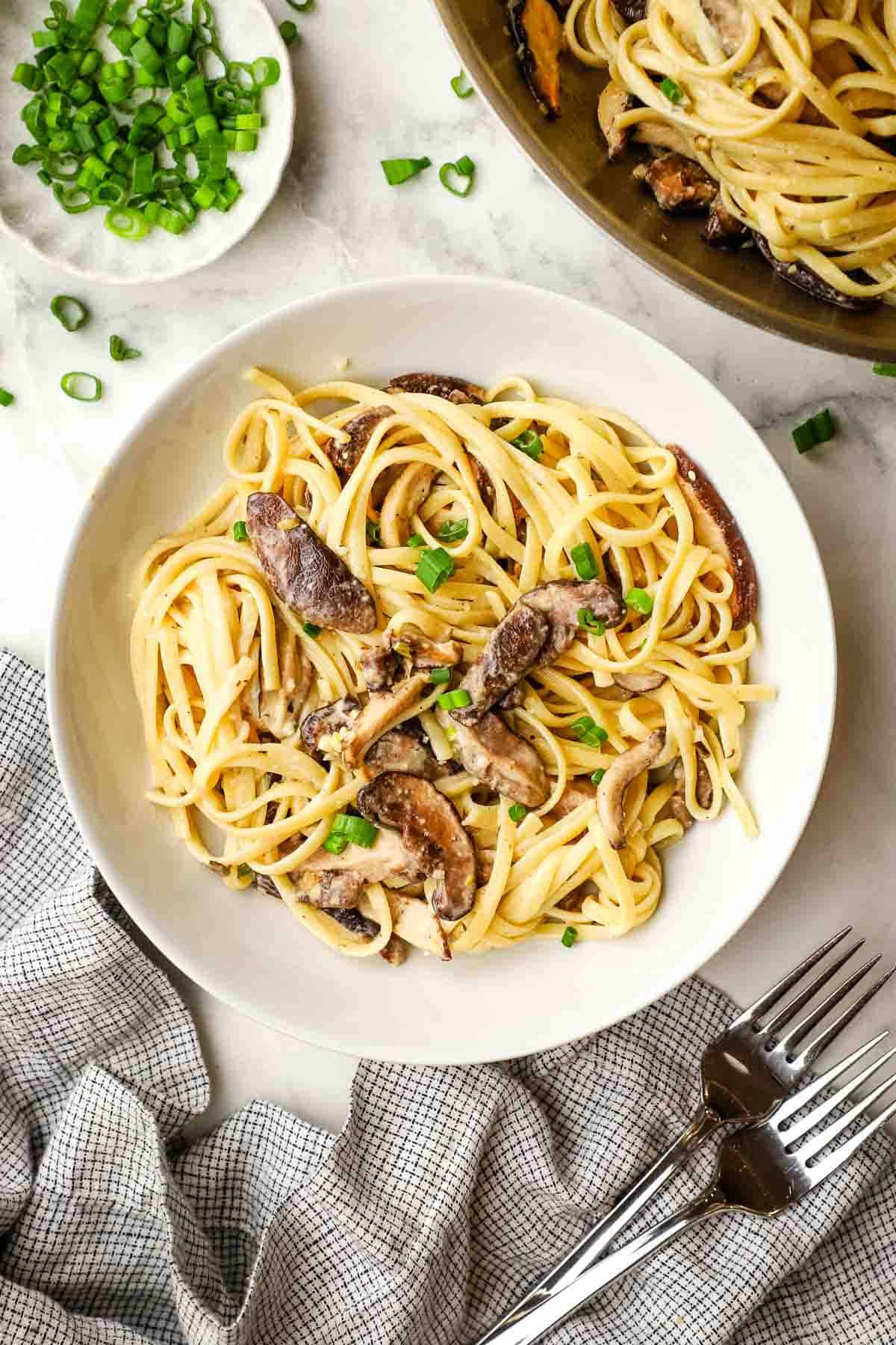 Miso mushroom pasta in a white bowl garnished with parsley.