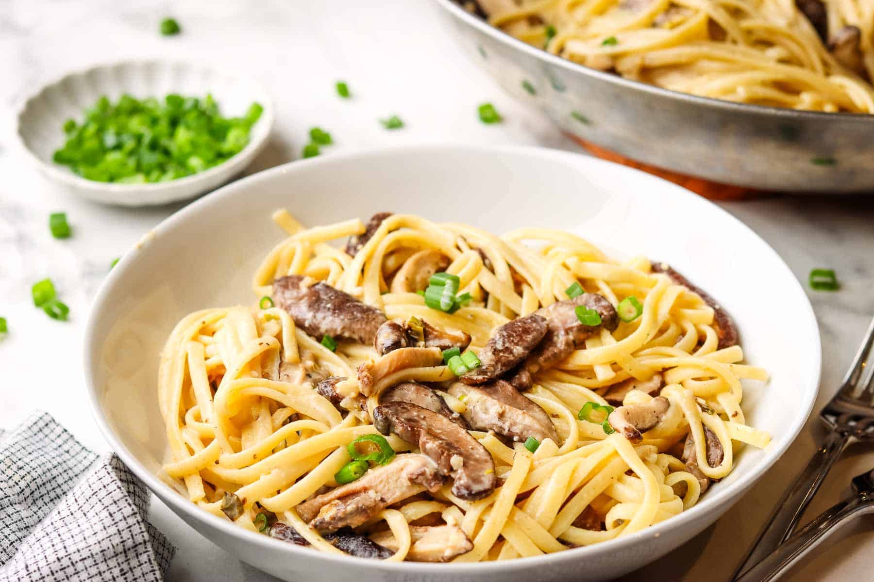 A bowl of miso mushroom pasta garnished with green onions.