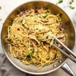 A pan of miso mushroom pasta with tongs for serving.