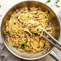 A pan of miso mushroom pasta with tongs for serving.