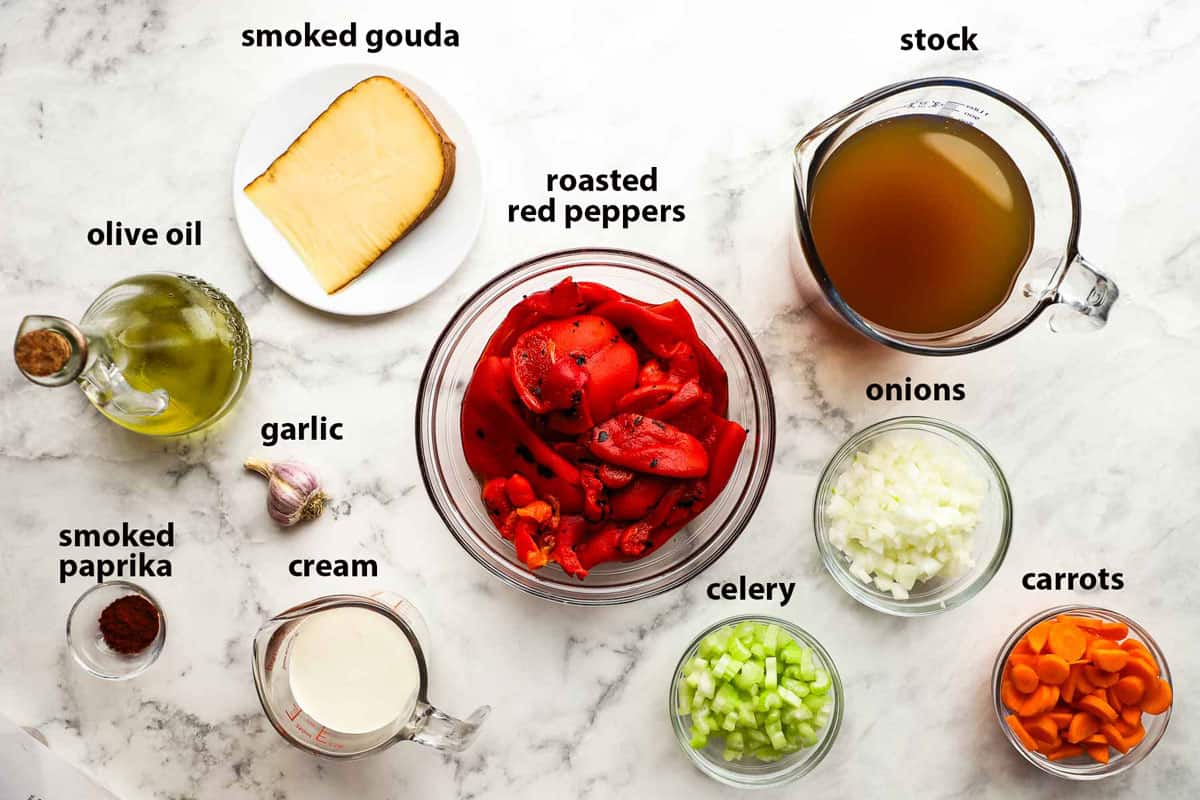 Top-down view of ingredients in bowls for Roasted Red Pepper and Gouda Soup ingredients that include roasted red peppers, smoked Gouda cheese, garlic, carrots, onions, celary and more.