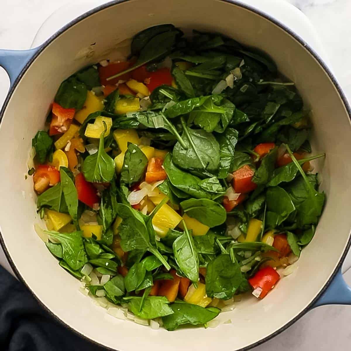 Spinach, bell peppers add to the cooking onions and garlick for baked orzo.