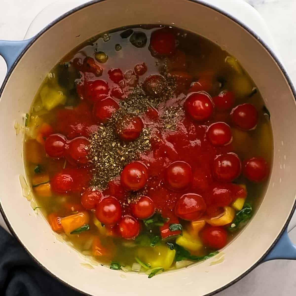 Chicken stock, cherry tomatoes, and spices were added to the large Dutch oven and simmering.