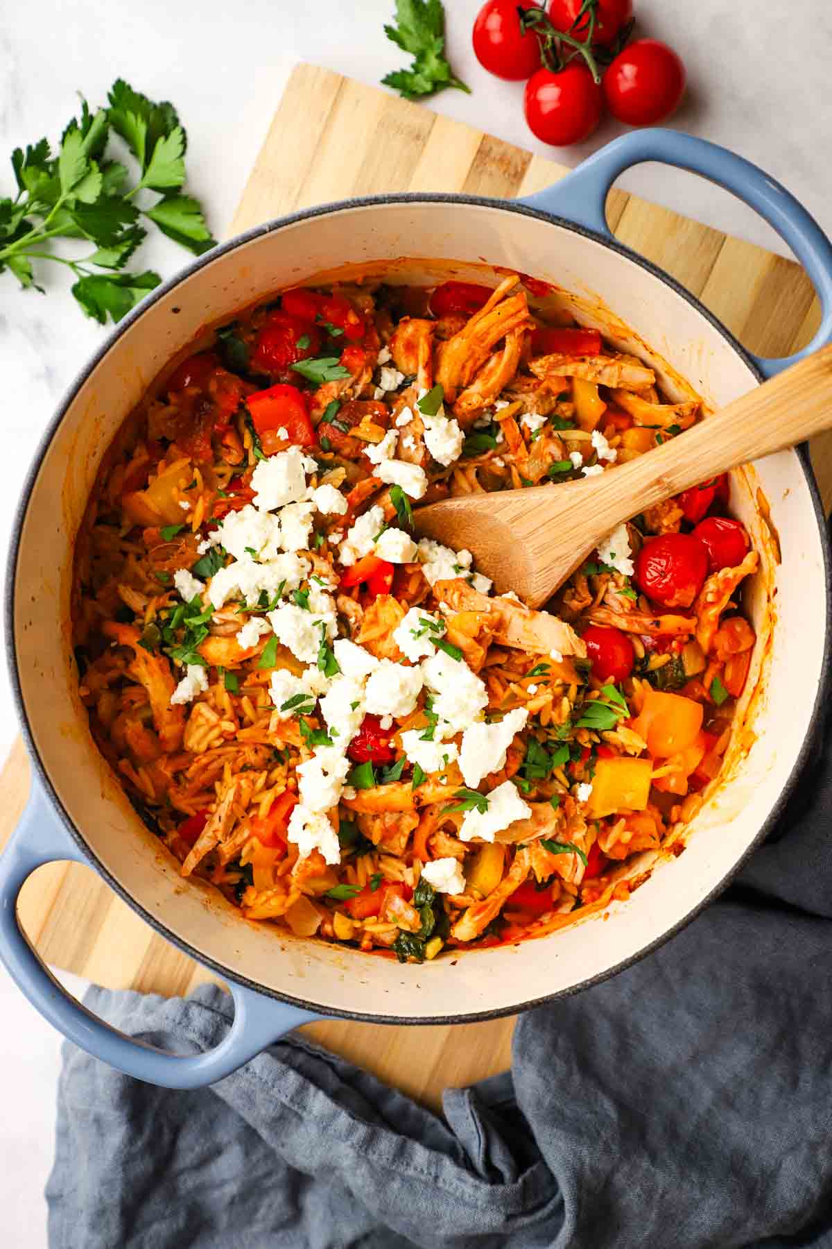 A pot of baked chicken and orzo garnished with feta and parsley.