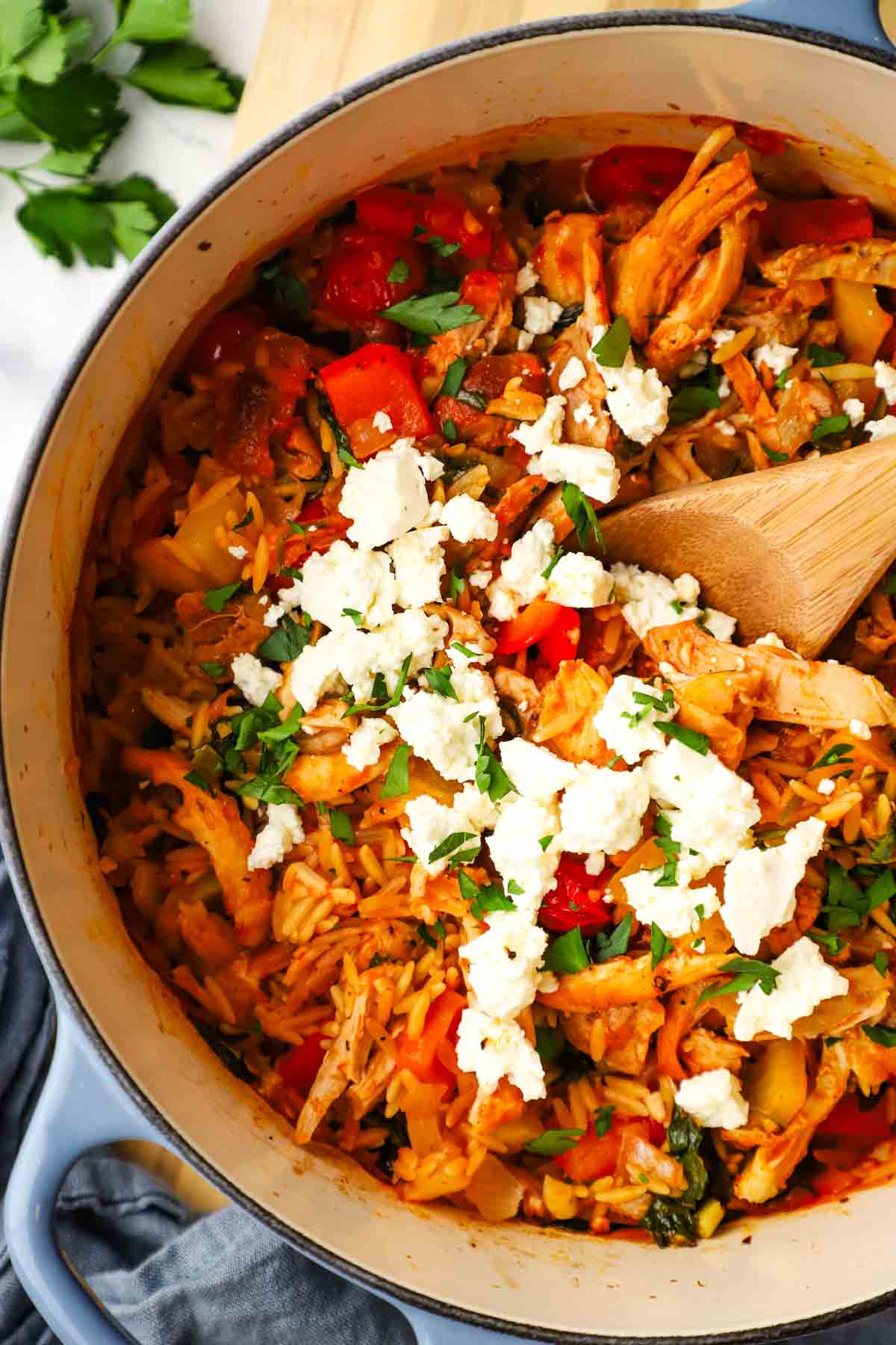 Closeup of a pot of vegetable chicken and orzo topped with feta.