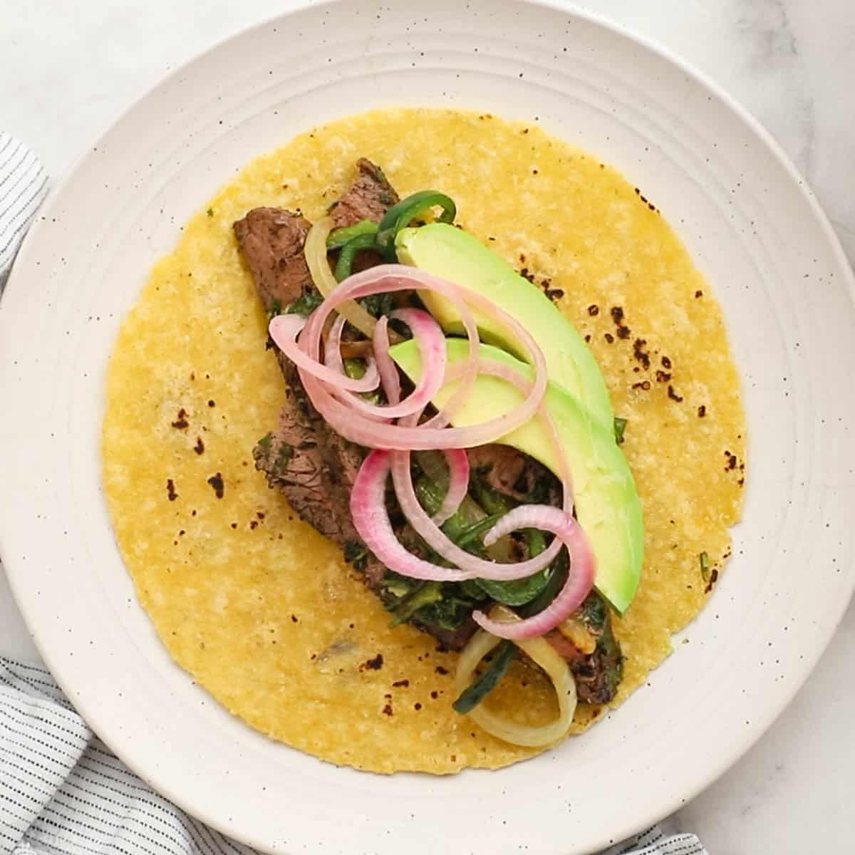 a soft taco filled with steak sloces and different toppings