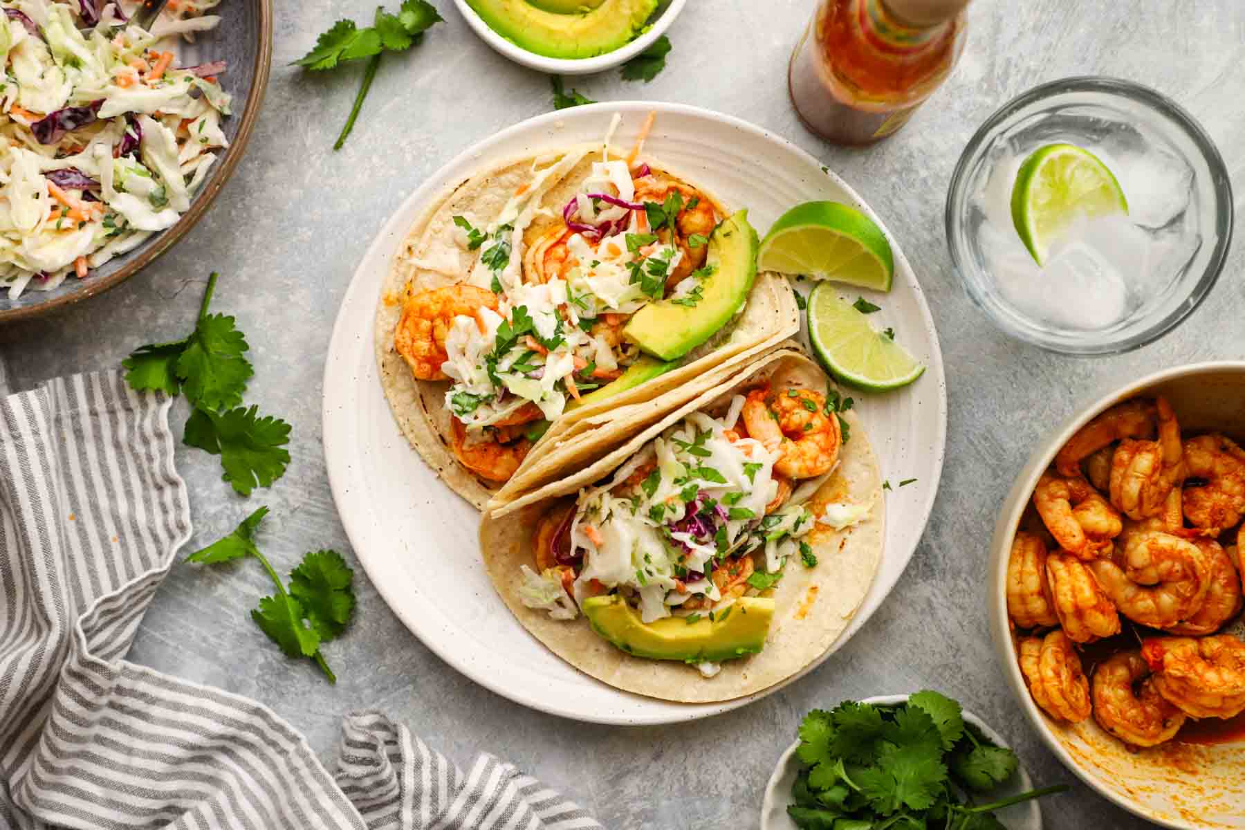 overhead view of 2 tacos with grilled shrimp, slaw, and avocado slices
