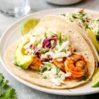 a shrimp taco on a plate with slaw.