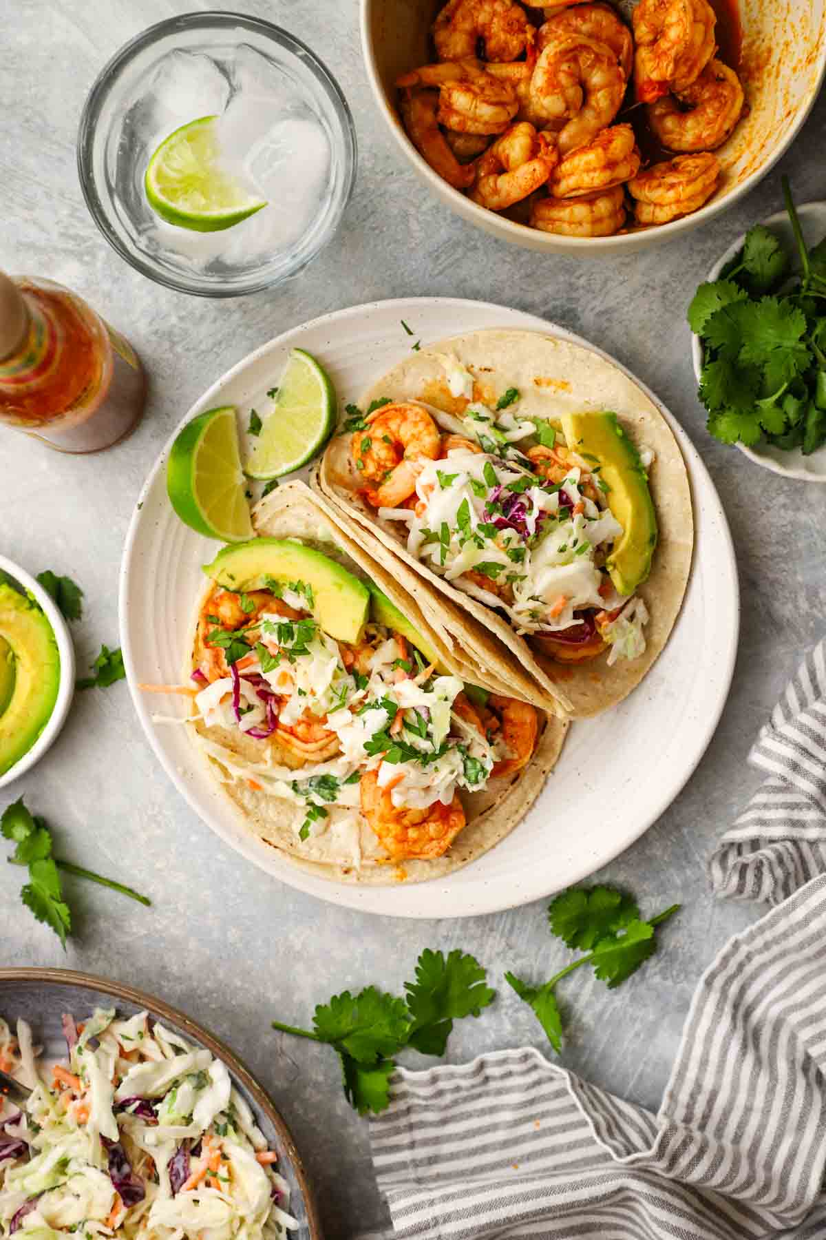 overhead view of two tacos on a plate with shrimp and coleslaw in them.