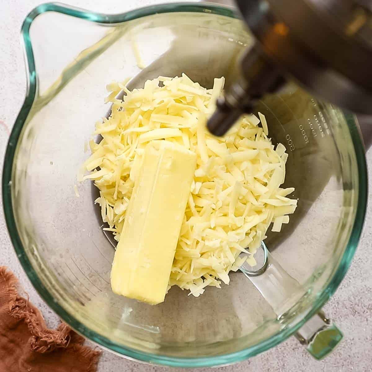 butter and shredded cheese in the bowl of a stand mixer